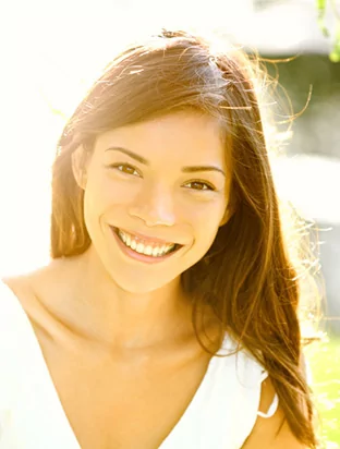 A young woman smiling in the sunlight free of frena issues.